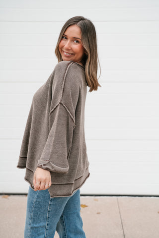 Side view of the washed brown dolman sleeve sweater showing the drop shoulder and side slit