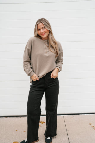 Woman wearing the Hidden Valley mocha thermal henley long sleeve top with black wide-leg pants and sneakers