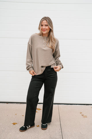 Front view of the relaxed mocha thermal long sleeve top with button henley neckline and black pants