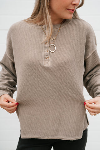 Close-up of the mocha thermal top's henley buttons, exposed seams and side slit hem