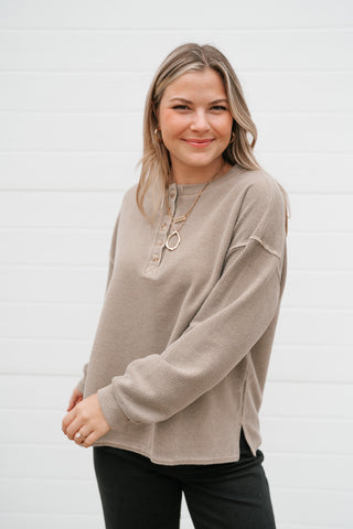Smiling model in the relaxed mocha thermal henley long sleeve top with black pants
