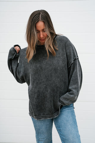Model with hand in jeans pocket wearing the oversized charcoal crew neck sweater