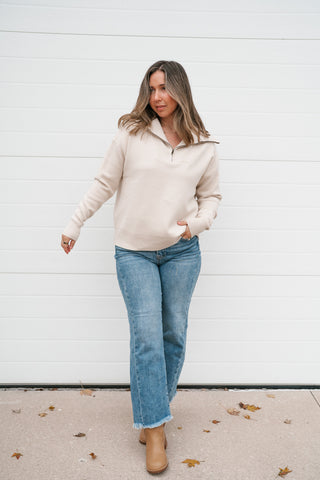 Full-length view of the cream quarter zip sweater styled with straight-leg jeans and tan ankle boots