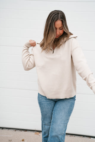 Three-quarter view of the cream quarter zip sweater showing the relaxed fit and long sleeves