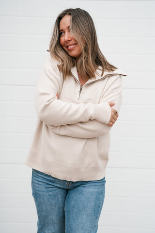 Smiling model with arms crossed in the cozy cream quarter zip pullover sweater