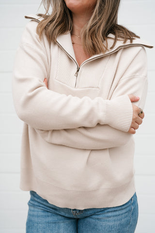 Close-up of the cream quarter zip pullover's collar, zip front and ribbed cuffs