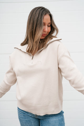 Front view of the relaxed cream quarter zip sweater showing the hip-length hem