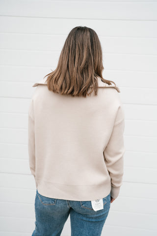 Back view of the cream quarter zip sweater showing the collar and drop shoulders