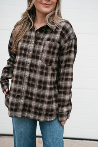 Close-up of the chocolate plaid button down top showing the collar, chest pocket and button front