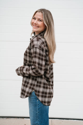 Side view of the brown plaid long sleeve button down top showing the curved shirttail hem