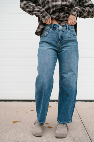 Model holding the waistband of the high rise medium wash slouchy barrel jeans