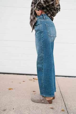 Side view of the high rise medium wash barrel jeans showing the fit through the hip