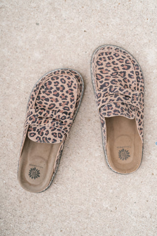 A pair of slip-on loafers with a leopard print pattern, laid flat on a textured concrete surface. The shoes feature a tan base with black and dark brown leopard spots, and the brand name 'YELLOWBOX' is visible on the insoles.